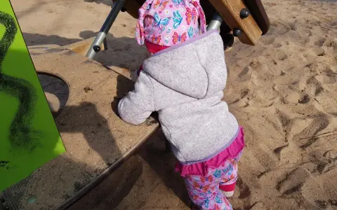 Kleines Kind auf dem Spielplatz, das die Welt erkundet. Manchmal sind die Nachteile der bindungsorientierten Erziehung, dass Kinder sich schwerer lösen können.