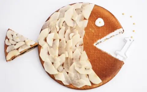 Gâteau en forme de poisson pour enfant, décoré de fines tranches de poire. Une part a été retirée, comme si le poisson mangeait.