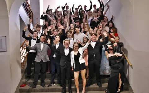 Schüler feiern Mottowoche Filme und Serien auf einer Treppe, alle in schicken Outfits, viele mit V-Gesten.