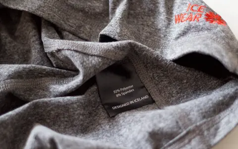 Szara koszulka z poliestru i spandexu, z haftem "ICE WEAR". Idealna na chłodne dni, zapewnia komfort i trwałość.