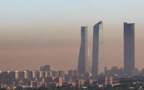 Edificios altos se alzan en una bruma densa, sugiriendo una ciudad mas contaminada del mundo.