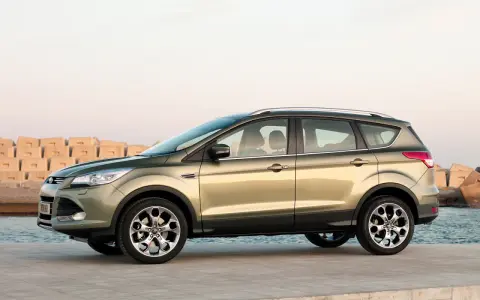 Złoty SUV Ford Kuga stoi na nabrzeżu przy morzu.