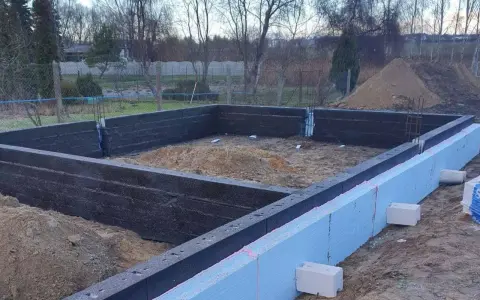 Budowa domu: fundamenty z bloczków fundamentowych i styropianu. Widać zbrojenie i przygotowanie pod wylewanie betonu.