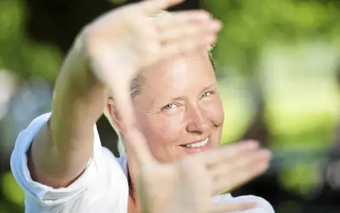 Regina Lund ler inramad av sina händer, som om hon skapar en scen för en film.
