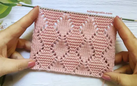 Muestra de tejido rosa con rombos a dos agujas patrones calados, ideal para prendas delicadas.