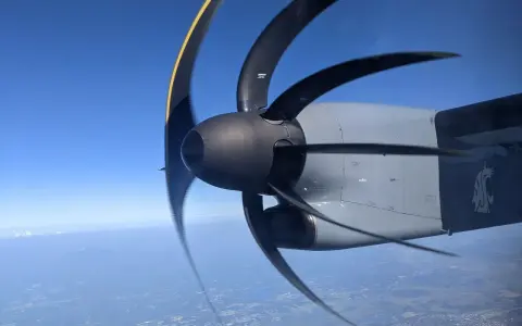 Wirujący śmigłowiec samolotu z efektem rolling shutter nad miastem i górami w oddali.