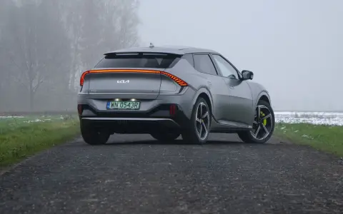 Szare Kia EV6 GT z żółtymi zaciskami hamulcowymi na tle mglistego krajobrazu.