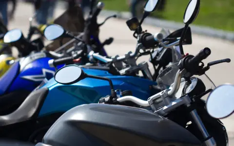Manillar de moto con espejos y parte del depósito. Un carnet de moto a punto de ser usado.