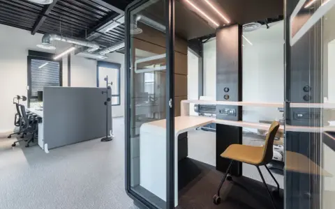 Un bureau moderne avec des cabines acoustiques et du mobilier flex office, idéal pour la concentration.