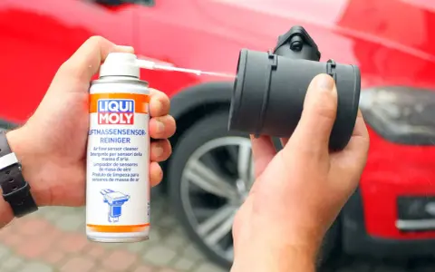 Czyszczenie przepływomierza: ręka trzyma puszkę preparatu Liqui Moly i aplikuje go na element.