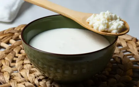 Un bol de kéfir, un probiotique naturel pour soulager le ballonnement, avec une cuillère en bois contenant des grains de kéfir.