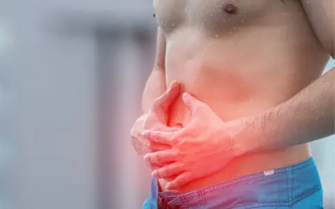 Homme tenant son ventre, zone rouge indiquant une douleur, possible déchireure abdominaux.