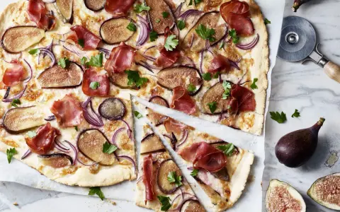 Ein köstlicher Flammkuchen mit Feigen, Schinken und roten Zwiebeln, garniert mit Petersilie.