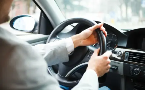 Mężczyzna za kierownicą zastanawia się, czy autocasco warto. Bezpieczeństwo na drodze to podstawa.