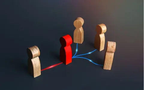 Figuras de madera conectadas por líneas de luz. Una figura roja central actúa como nodo, conectando a otras figuras, representando el papel de intermediarios financieros.