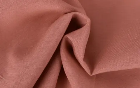 Tessuto twill color salmone, ideale per capi invernali o estivi, con pieghe morbide che ne esaltano la trama.