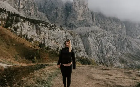 Kobieta na tle majestatycznych gór w Val di Funes. Mgła otula szczyty, tworząc mistyczną atmosferę.