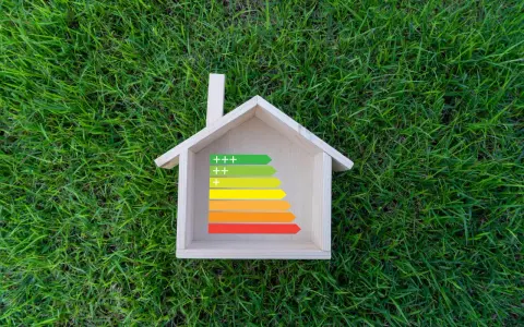 Casa de madera sobre césped con etiqueta de eficiencia energética, ideal para calefacción sostenible.
