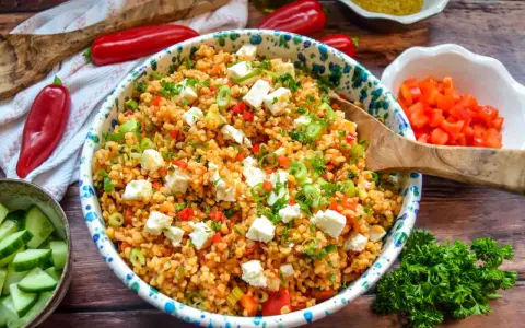 Frischer bulgursalat mit feta, Tomaten, Paprika und Frühlingszwiebeln, garniert mit Petersilie.