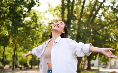 Jeune femme rayonnante dans un parc, profitant de la nature. Elle semble ressentir les bienfaits de la L-tyrosine pour son bien-être.