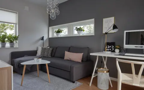 Snyggt hemmakontor med mörkgrå vägg, soffa, skrivbord och dator. Inspiration för ett modernt och stilrent arbetsrum.