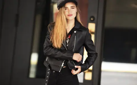 Dziewczyna w czarnej ramonesce i czapce, emanująca pewnością siebie w stylu glam rock.