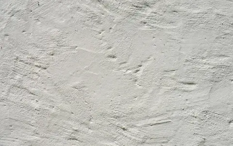Texture d'enduit à la chaux blanc, présentant des irrégularités et des taches subtiles, témoignant de son application manuelle.