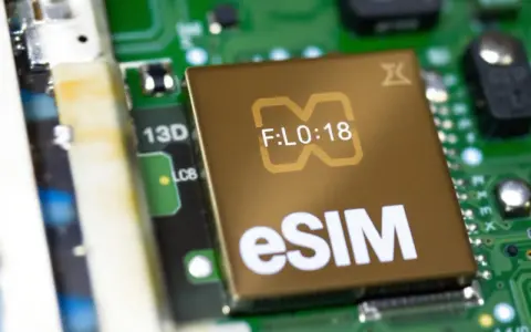 Närbild på ett gyllene chip med texten "eSIM" och en stiliserad symbol. Detta digitala simkort är en del av ett kretskort.