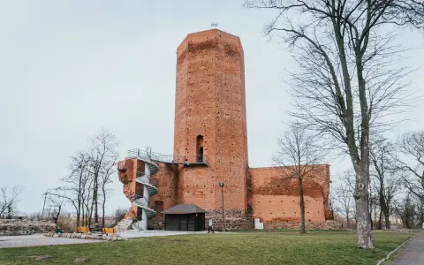 Wysoka, ceglana wieża w mieście, przypominająca mysią wieżę, z kręconymi schodami na zewnątrz.