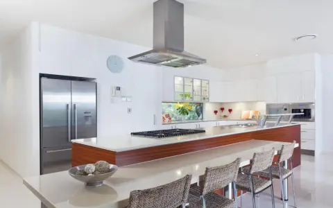 Cocina moderna con isla, electrodomésticos de acero inoxidable y encimera de cuarzo. Ideal para calcular el reforma cocina precio aproximado.