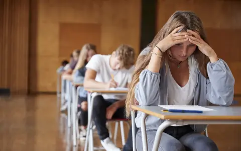 En tjej med händerna mot pannan känner efter studenten ångest under ett prov.