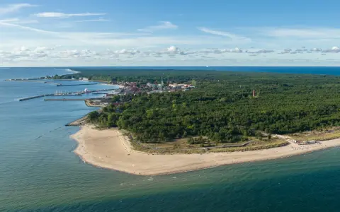 Widok na zatokę pucką z lotu ptaka. Widać piaszczystą plażę, las sosnowy, miasteczko z portem i latarnię morską.