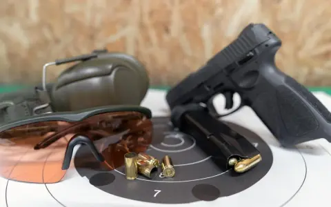 Pistolet, magazynek, łuski, okulary ochronne i słuchawki – kompletne akcesoria strzeleckie gotowe do użycia.