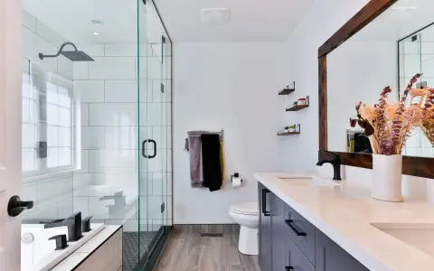 Baño moderno con ducha de cristal, inodoro, lavabo doble y un gran espejo. Las ventanas para baños pequeños son clave para la luminosidad.