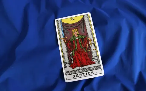 Karta XI Sprawiedliwość z talii tarot na niebieskim tle. Królowa z mieczem i wagą symbolizuje równowagę i prawdę.