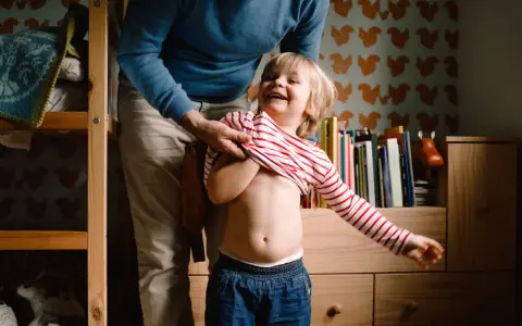 Padre viste a su hijo, quien ríe a carcajadas. A pesar de que mi hijo cada vez se porta peor, estos momentos son oro.