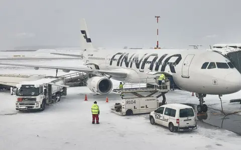 Samolot Finnair na lotnisku w śnieżny dzień. Pracownicy obsługi naziemnej przygotowują samolot do lotu. Czy do Finlandii można lecieć na dowód?