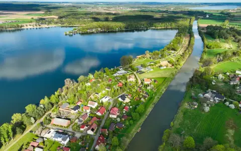 Pławniowice jezioro otoczone zielenią i domkami letniskowymi, z kanałem wodnym biegnącym wzdłuż brzegu.