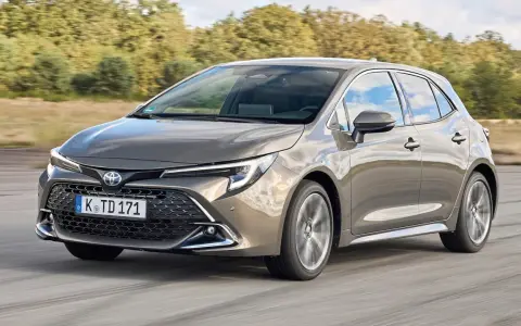 Grauer Toyota Corolla 2.0 Hybrid fährt auf Straße. Mögliche Probleme mit dem Hybridantrieb sind hier kein Thema.