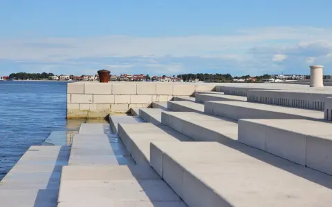 Kamienne schody nad morzem, z widokiem na miasto w oddali. Zadar co warto zobaczyć - idealne miejsce na spacer.