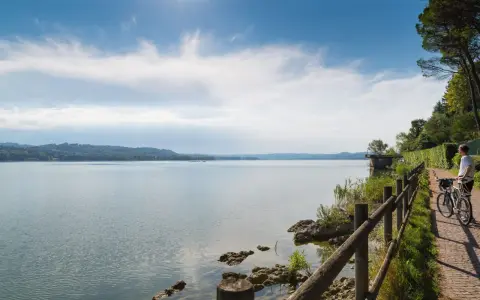 Ciclista ammira un lago in Lombardia, godendosi una delle tante ciclabili panoramiche.
