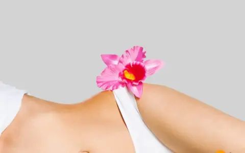 Delikatna różowa orchidea na tle kobiecego ciała, symbolizująca naturalne piękno i różnorodne rodzaje warg sromowych.