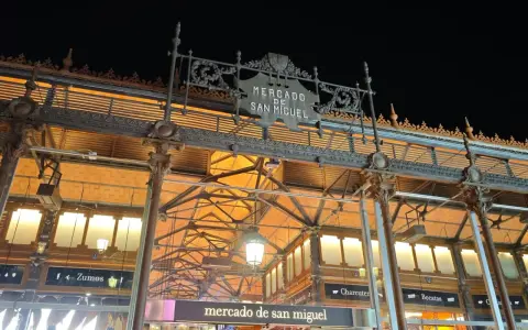Das Mercado de San Miguel bei Nacht, mit seinem verzierten Eingang und den Lichtern, die durch das Glasdach scheinen.