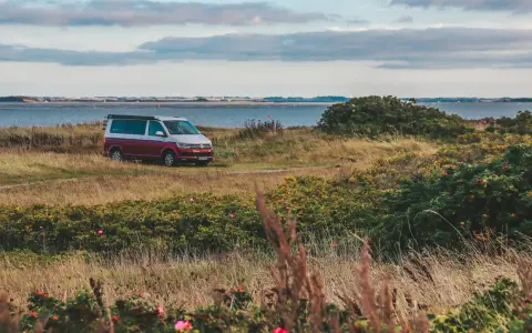 Husbil parkerad vid en kustväg i Danmark, redo för ett äventyr. En perfekt roadtrip danmark-upplevelse.