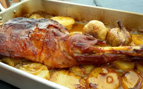 Paletilla de cordero asada al horno con patatas y ajos.