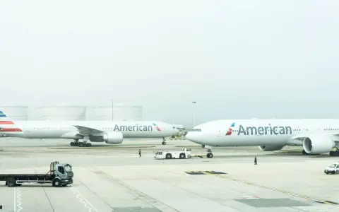 Dwa samoloty American Airlines na płycie lotniska, gotowe do przyjęcia bagażu rejestrowanego.