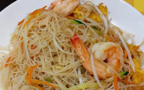 Spaghetti di riso con gamberi, carote, zucchine e germogli di soia. Un piatto leggero e gustoso.