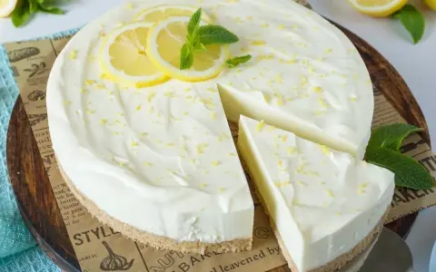 Cremige Philadelphia Torte mit Zitronenscheiben und Minze, ein Stück wurde bereits angeschnitten.
