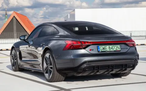 Tył ciemnoszarego Audi RS e-tron GT na parkingu, z widocznymi światłami i tablicą rejestracyjną.