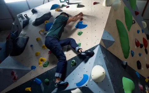 Mann klettert an einer bunten Kletterwand, die aussieht, als ob sie jemand selber bauen könnte.